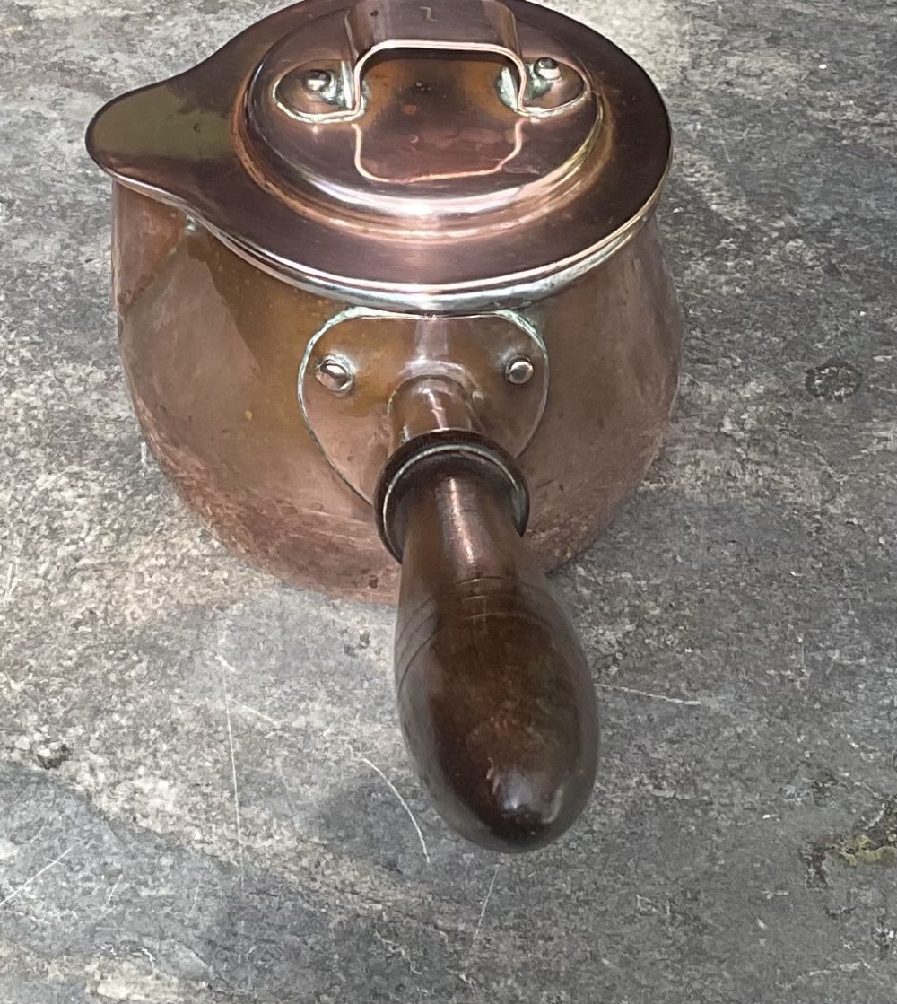 An 1830s Georgian copper brandy warmer featuring a polished copper vessel, fitted lid with loop handle, pouring spout, and an extended turned wooden handle. View III