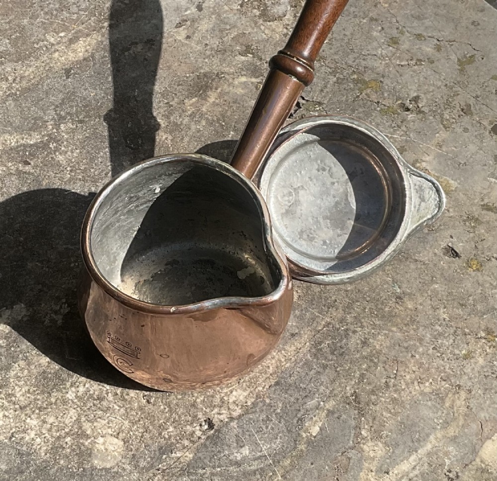 An 1830s Georgian copper brandy warmer featuring a polished copper vessel, fitted lid with loop handle, pouring spout, and an extended turned wooden handle. View VII
