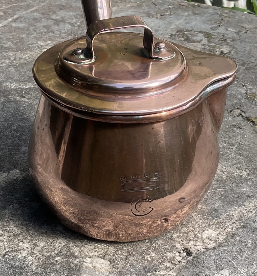 An 1830s Georgian copper brandy warmer featuring a polished copper vessel, fitted lid with loop handle, pouring spout, and an extended turned wooden handle. View VIII