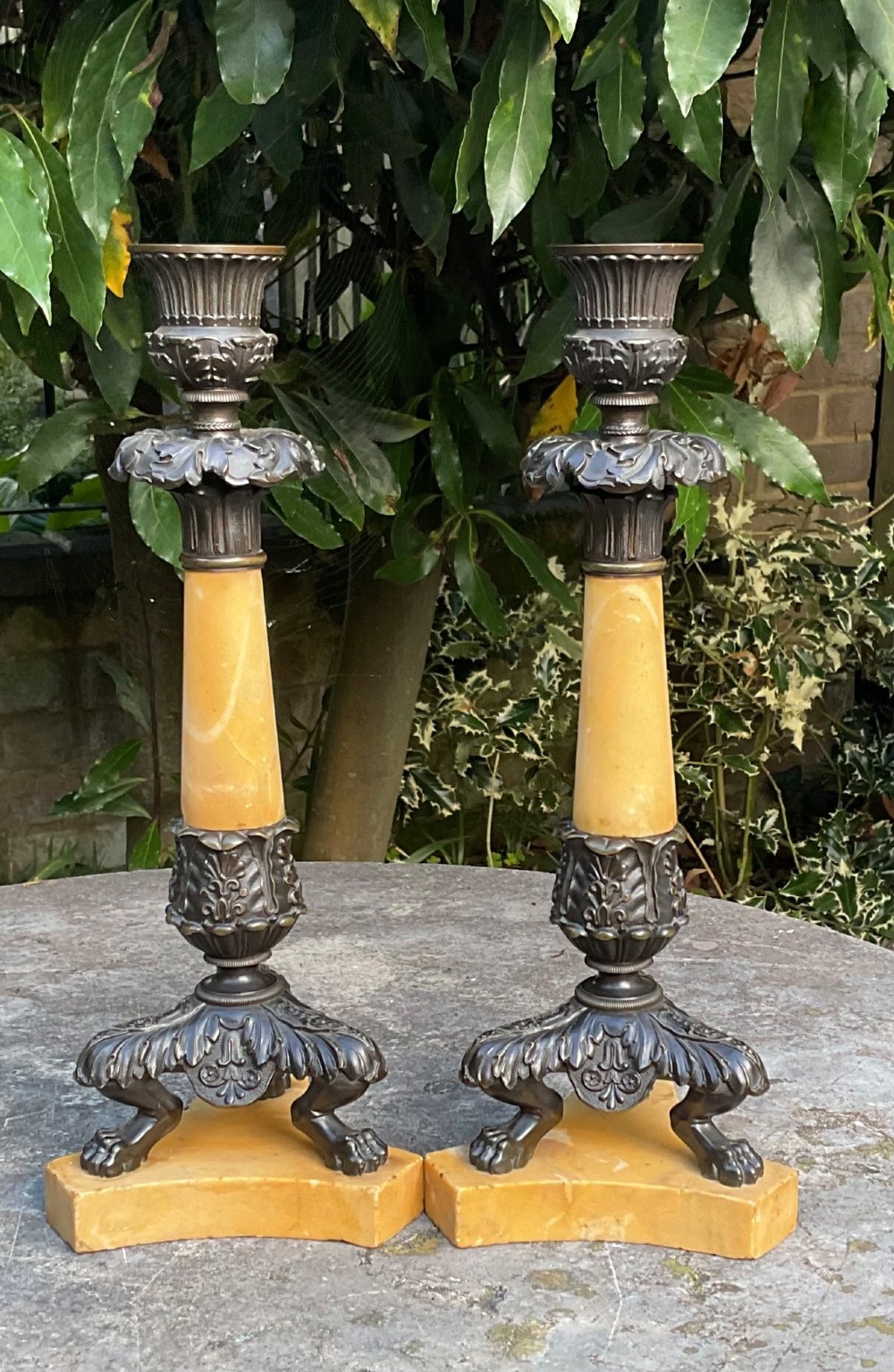 A pair of Regency period candlesticks with yellow marble column stems, classical dark bronze sconces, acanthus collars, and bronze paw feet on triform marble bases. View VII