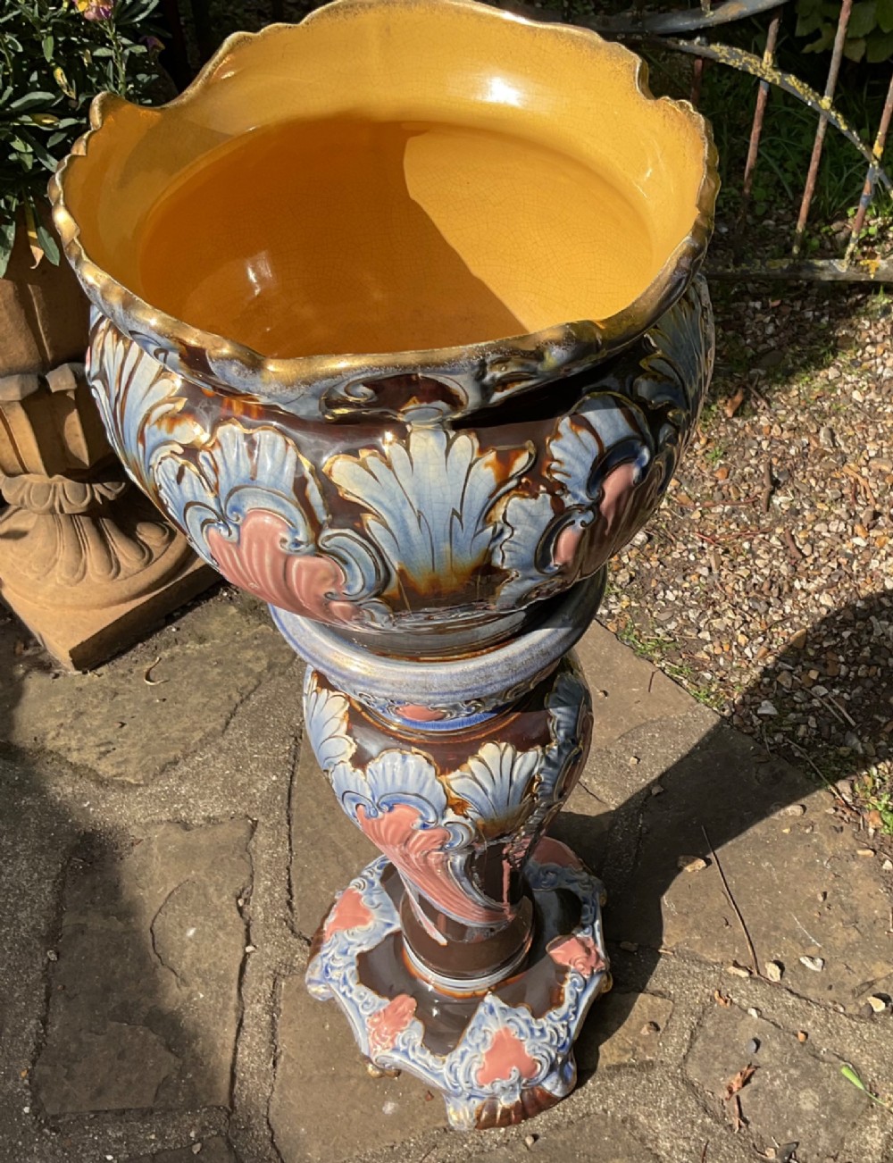 A late Victorian glazed majolica ceramic jardiniere resting atop a matching relief-moulded pedestal stand with brown, blue, and pink glazes. View II