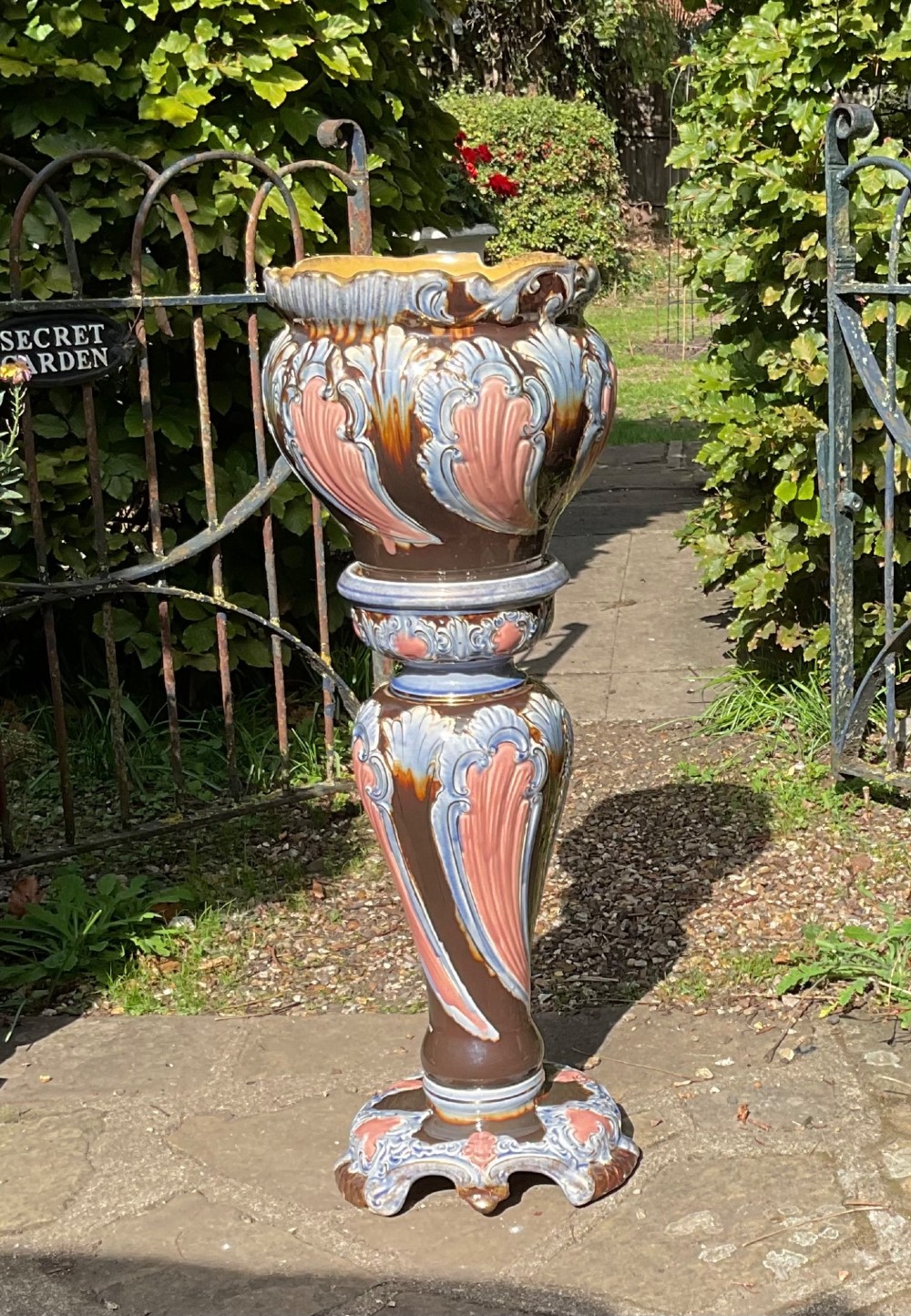 A late Victorian glazed majolica ceramic jardiniere resting atop a matching relief-moulded pedestal stand with brown, blue, and pink glazes. View VI