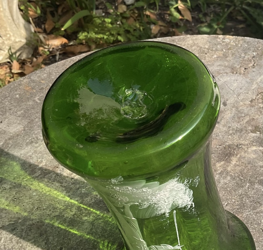 A flared emerald green glass vase featuring a hand-painted white enamel figure of a Victorian boy in a landscape. View II