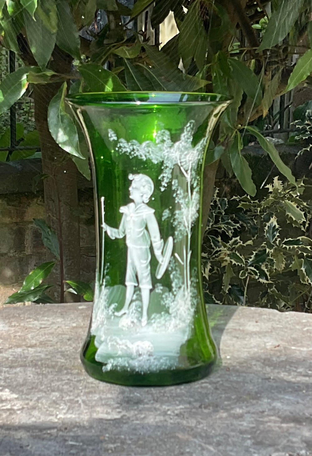 A flared emerald green glass vase featuring a hand-painted white enamel figure of a Victorian boy in a landscape. View III