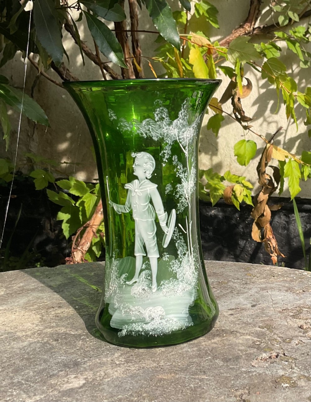 A flared emerald green glass vase featuring a hand-painted white enamel figure of a Victorian boy in a landscape. View IV
