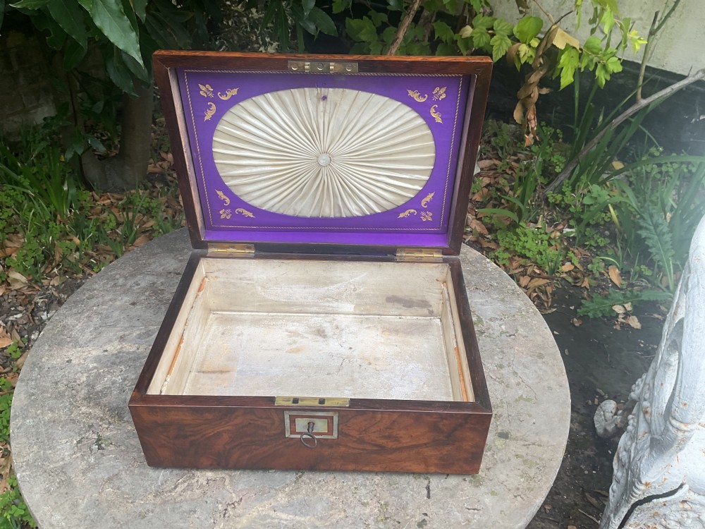 An open Victorian walnut sewing box featuring a fitted purple silk interior and a pleated cream silk panel on the inside lid. View III