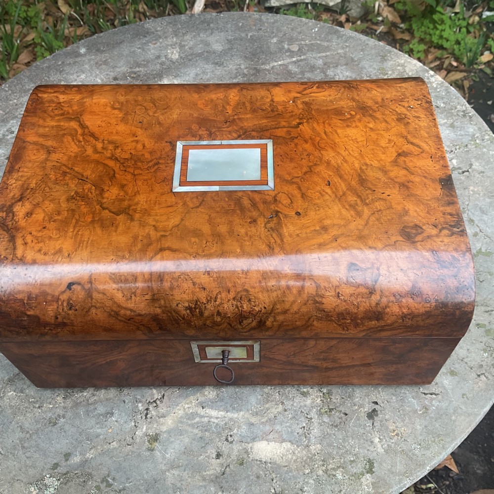 An open Victorian walnut sewing box featuring a fitted purple silk interior and a pleated cream silk panel on the inside lid. View V