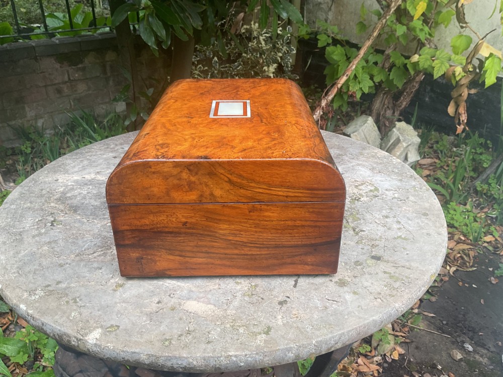 An open Victorian walnut sewing box featuring a fitted purple silk interior and a pleated cream silk panel on the inside lid. View VI
