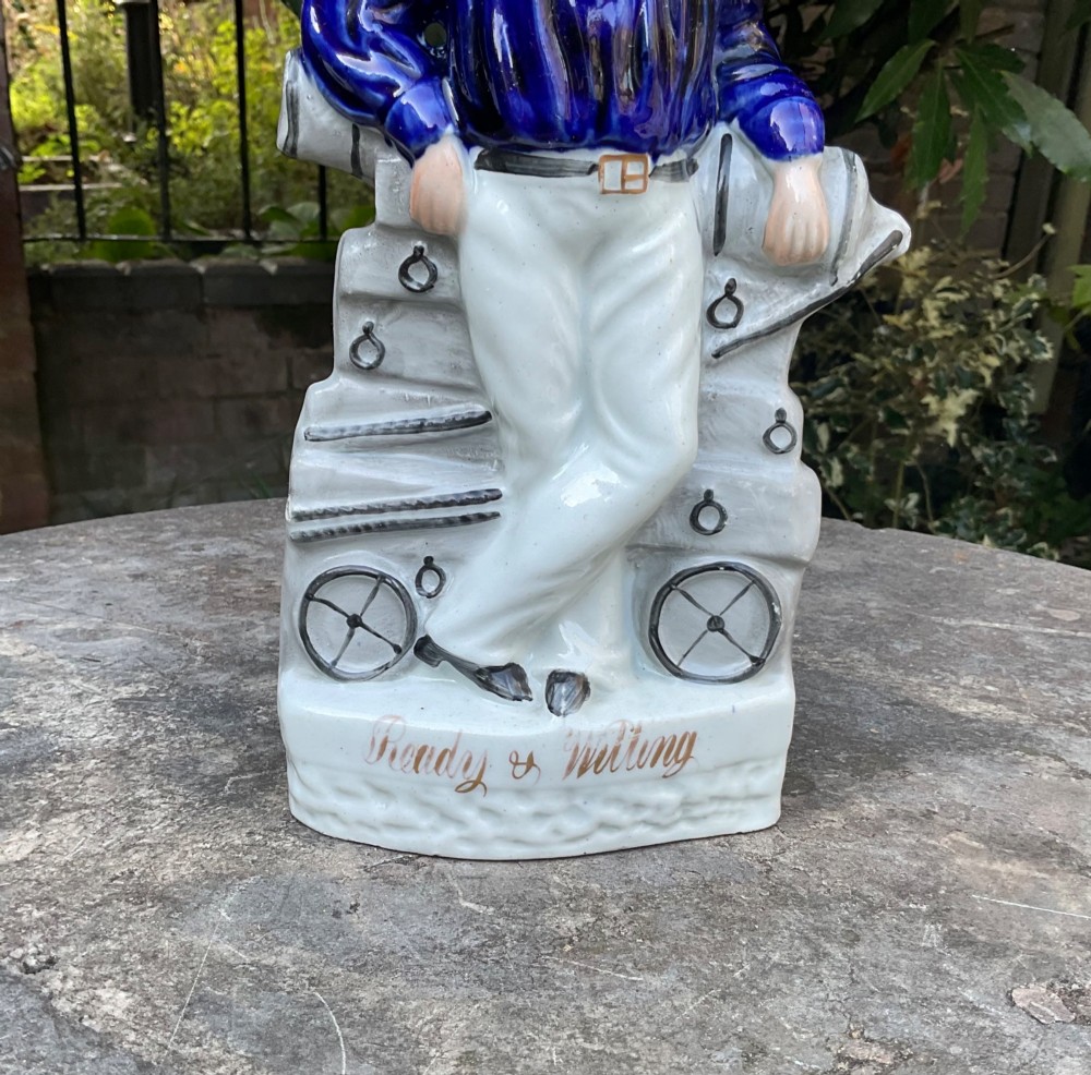 A Victorian Staffordshire earthenware figure depicting an English sailor leaning on a cannon with the base inscribed Ready and Willing. View II