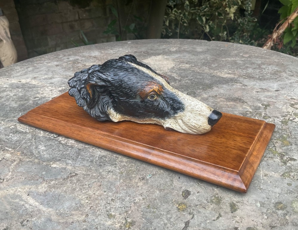A cold-painted bronze dogs head mounted as a spring-loaded letter clip on a rectangular polished wooden plinth. View VII