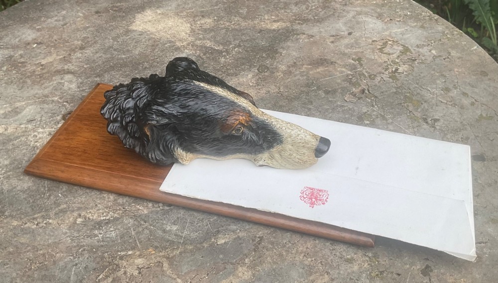 A cold-painted bronze dogs head mounted as a spring-loaded letter clip on a rectangular polished wooden plinth. View VIII