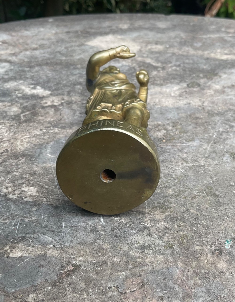 A cast brass car mascot depicting a standing Scottish highlander figure on a circular base inscribed with Phineas MacLino. View V
