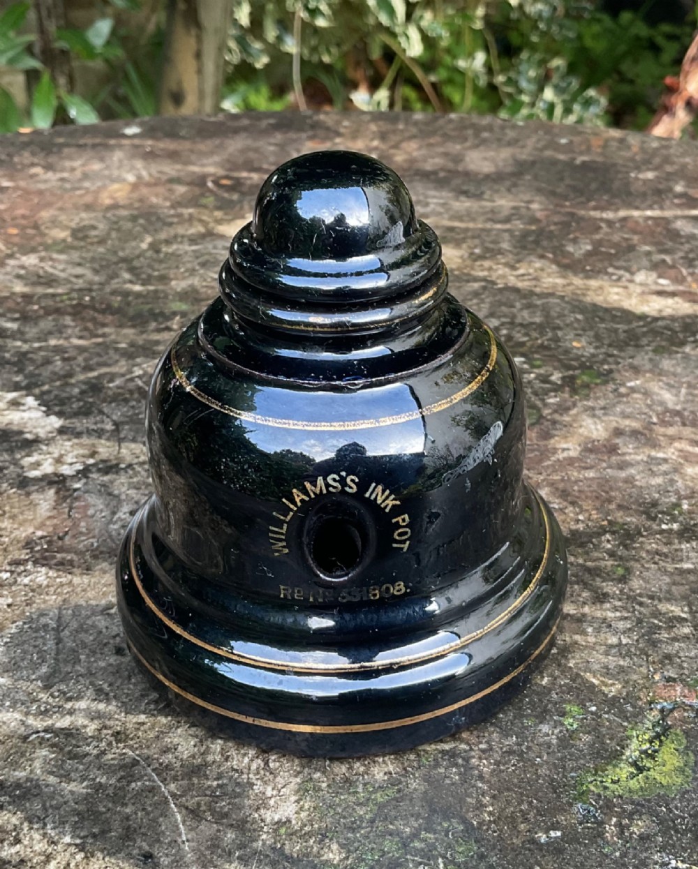 A domed black glazed pottery inkwell decorated with gilded concentric bands and transfer-printed lettering reading Jarrold and Sons Stationers. View II