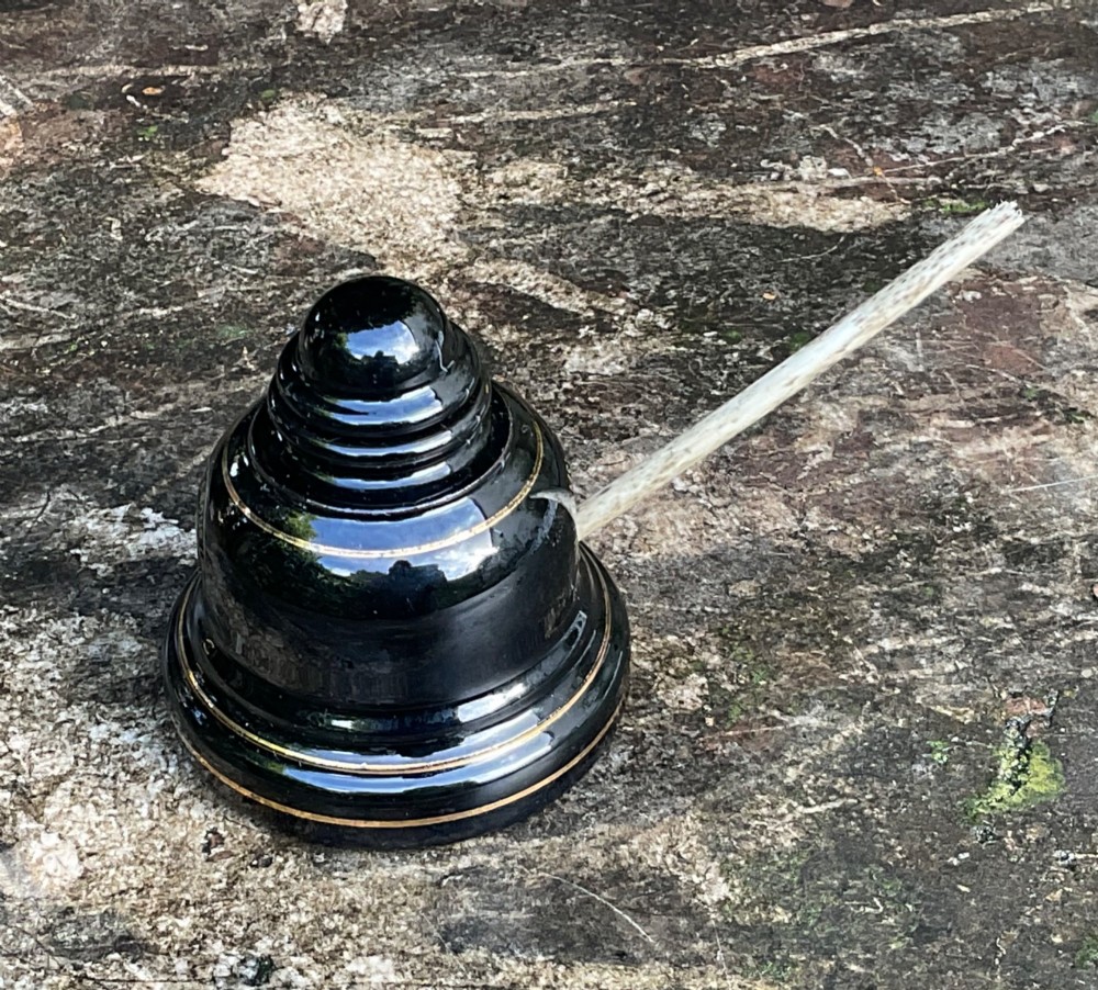 A domed black glazed pottery inkwell decorated with gilded concentric bands and transfer-printed lettering reading Jarrold and Sons Stationers. View IV