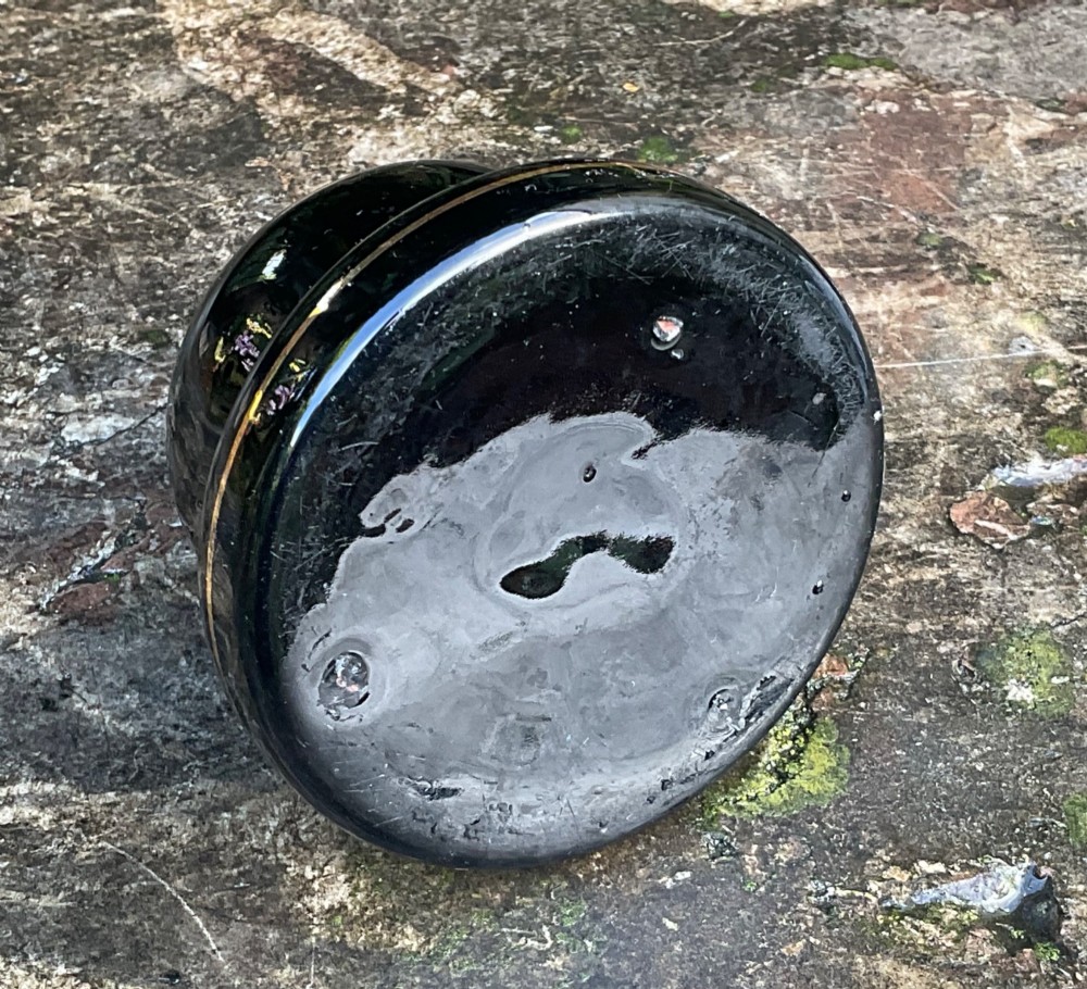 A domed black glazed pottery inkwell decorated with gilded concentric bands and transfer-printed lettering reading Jarrold and Sons Stationers. View V