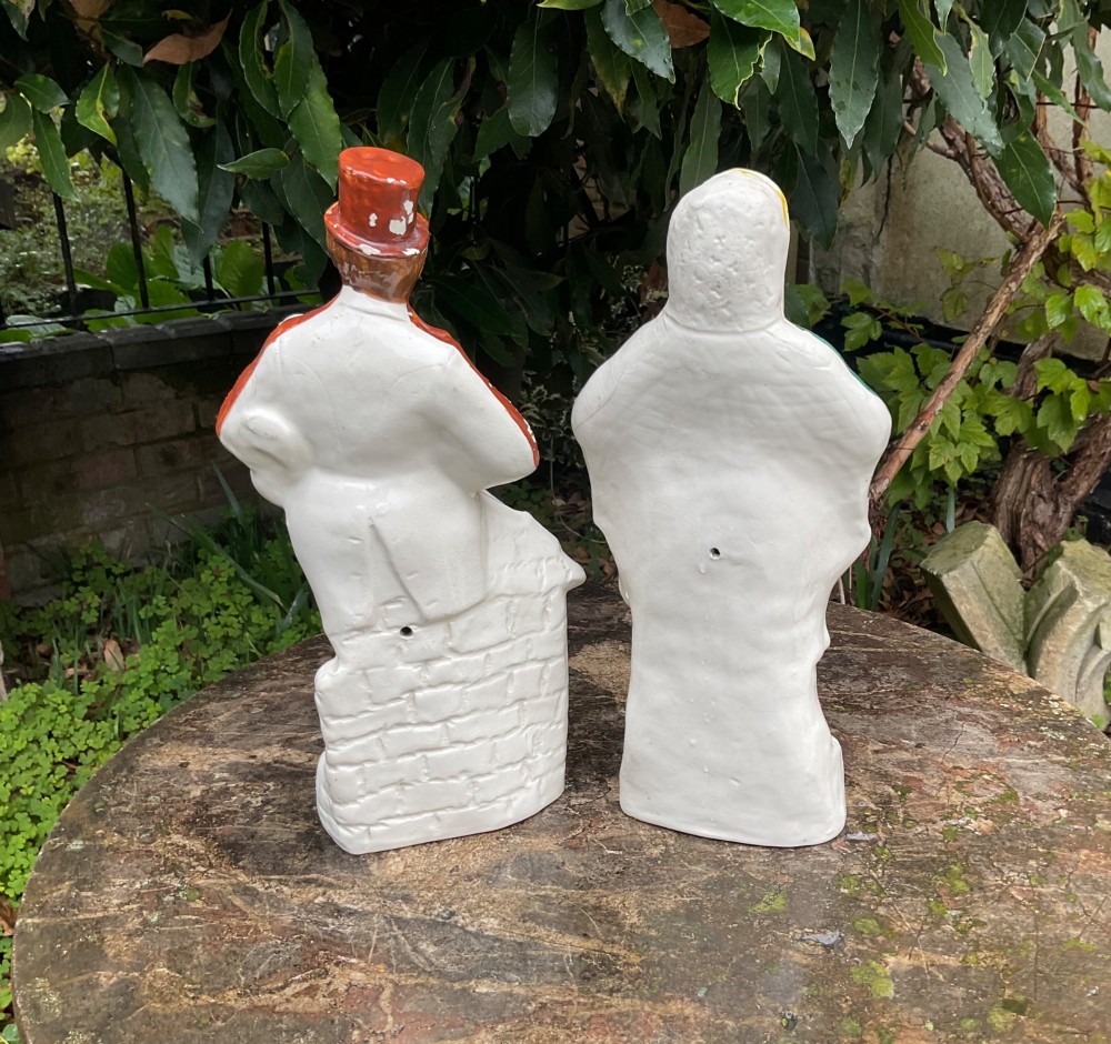 A pair of late Victorian Staffordshire earthenware flatback figures depicting an Irish piper in a red coat and an Irish colleen wearing a yellow headscarf. View V