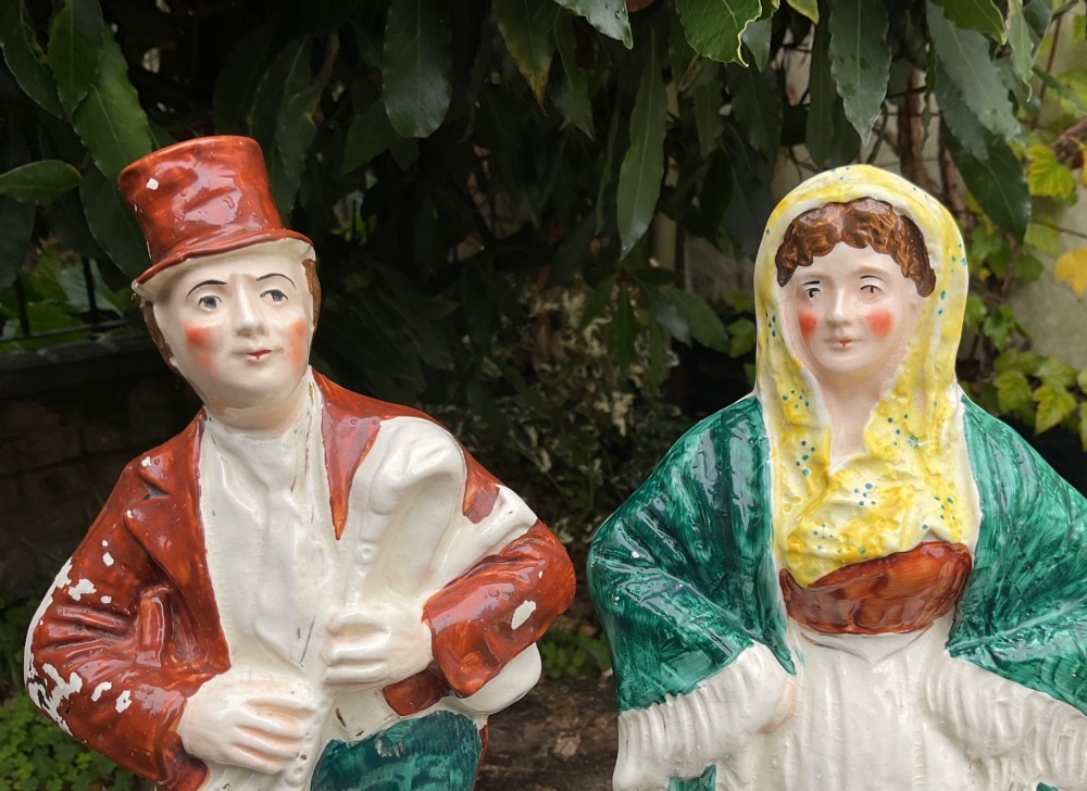 A pair of late Victorian Staffordshire earthenware flatback figures depicting an Irish piper in a red coat and an Irish colleen wearing a yellow headscarf. View VII