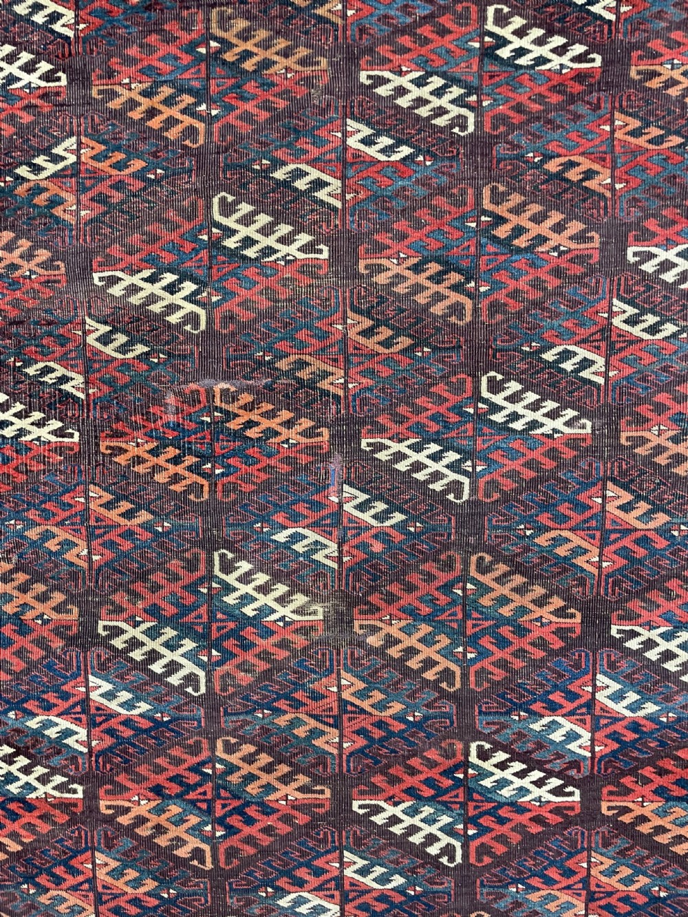 An antique Yomut Turkoman hand-knotted wool rug featuring repeating geometric diamond lattice motifs in deep red, navy blue, and ivory shades. View II