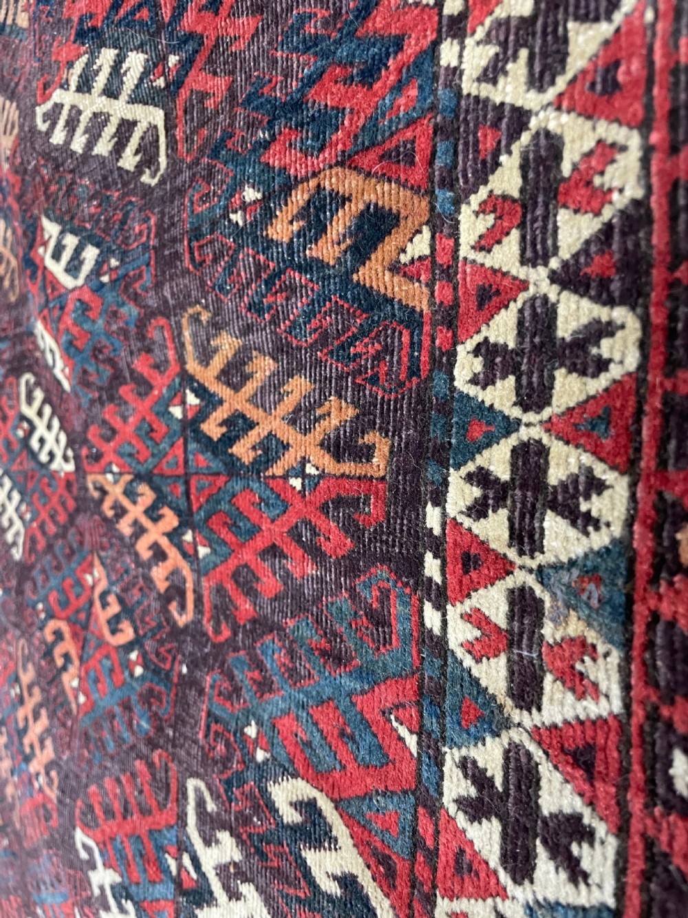 An antique Yomut Turkoman hand-knotted wool rug featuring repeating geometric diamond lattice motifs in deep red, navy blue, and ivory shades. View V