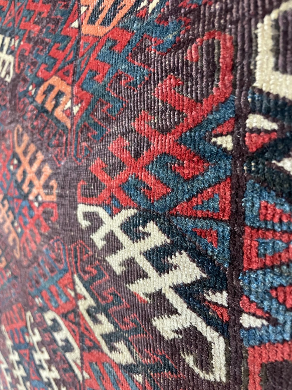 An antique Yomut Turkoman hand-knotted wool rug featuring repeating geometric diamond lattice motifs in deep red, navy blue, and ivory shades. View VI