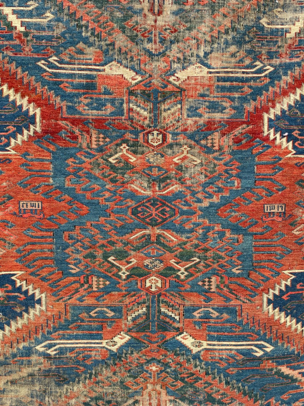 An antique Caucasian Dragon Soumak flatweave wool rug featuring geometric diamond medallions and dragon motifs in terracotta red, navy blue, and teal green. View II