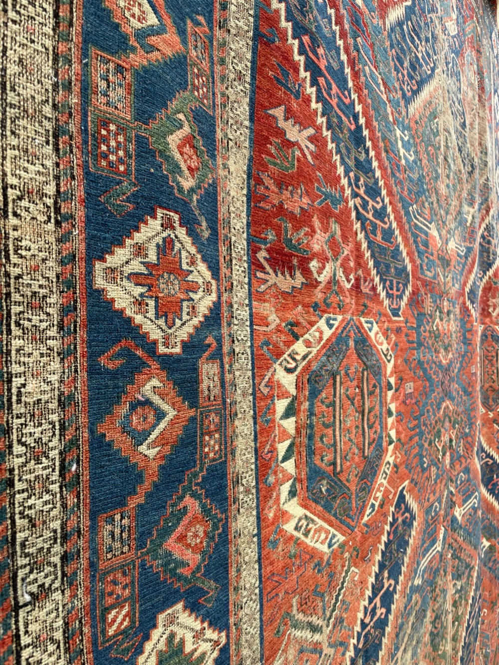 An antique Caucasian Dragon Soumak flatweave wool rug featuring geometric diamond medallions and dragon motifs in terracotta red, navy blue, and teal green. View III