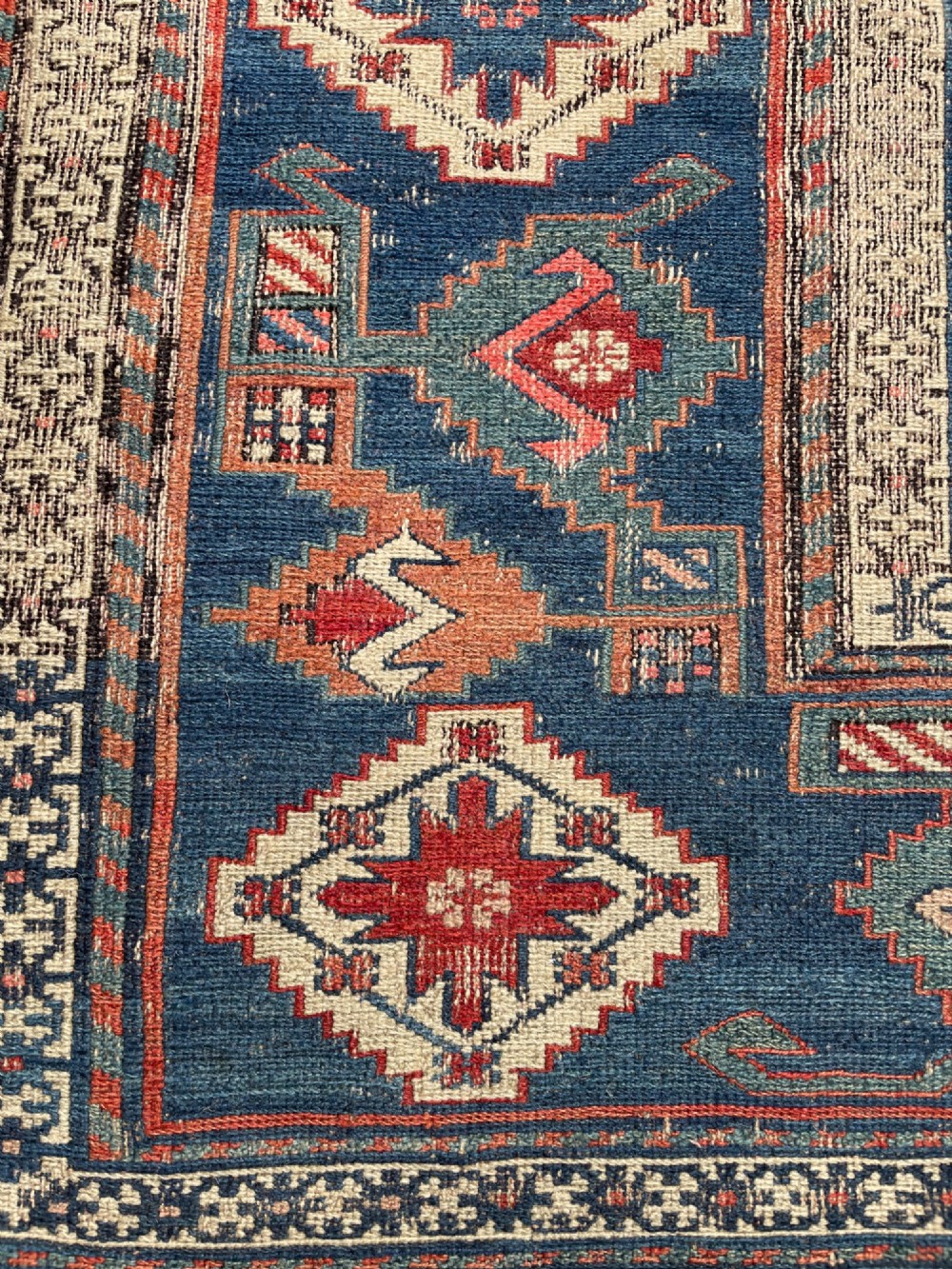 An antique Caucasian Dragon Soumak flatweave wool rug featuring geometric diamond medallions and dragon motifs in terracotta red, navy blue, and teal green. View IX