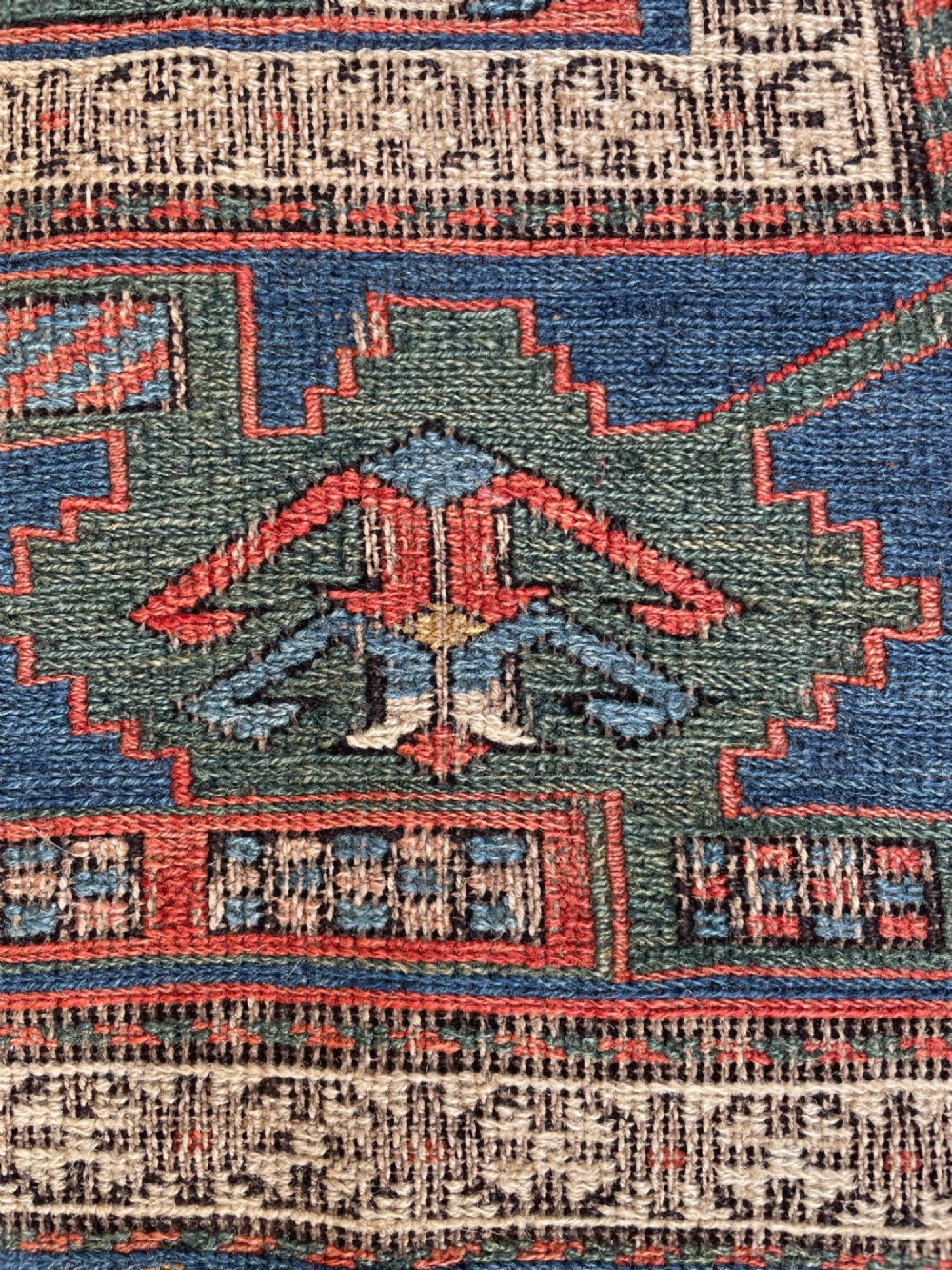 An antique Caucasian Dragon Soumak flatweave wool rug featuring geometric diamond medallions and dragon motifs in terracotta red, navy blue, and teal green. View XII