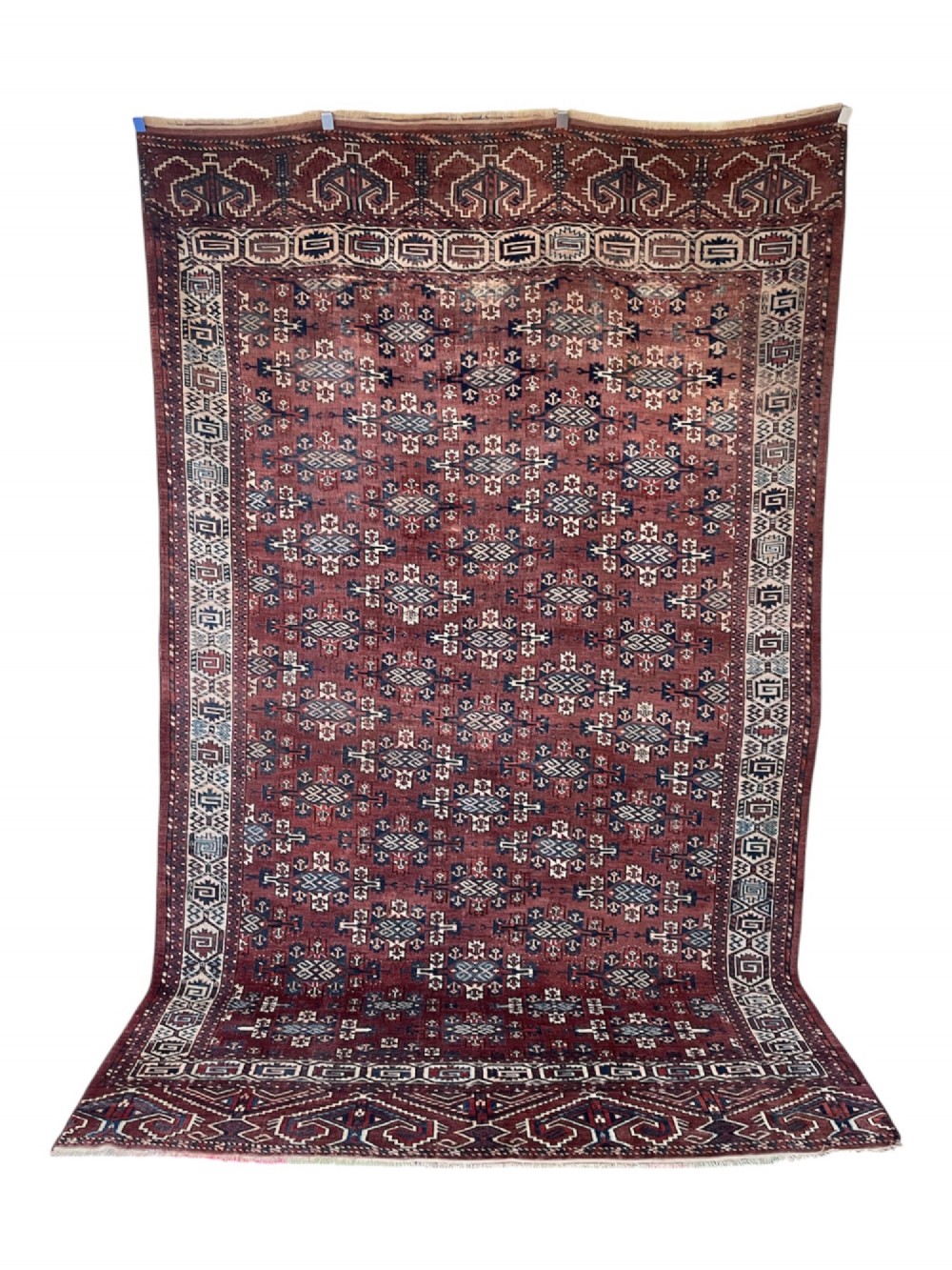 A large antique hand-knotted wool Turkoman Yomut carpet featuring repeating geometric gol motifs on a deep red ground surrounded by geometric borders. View II