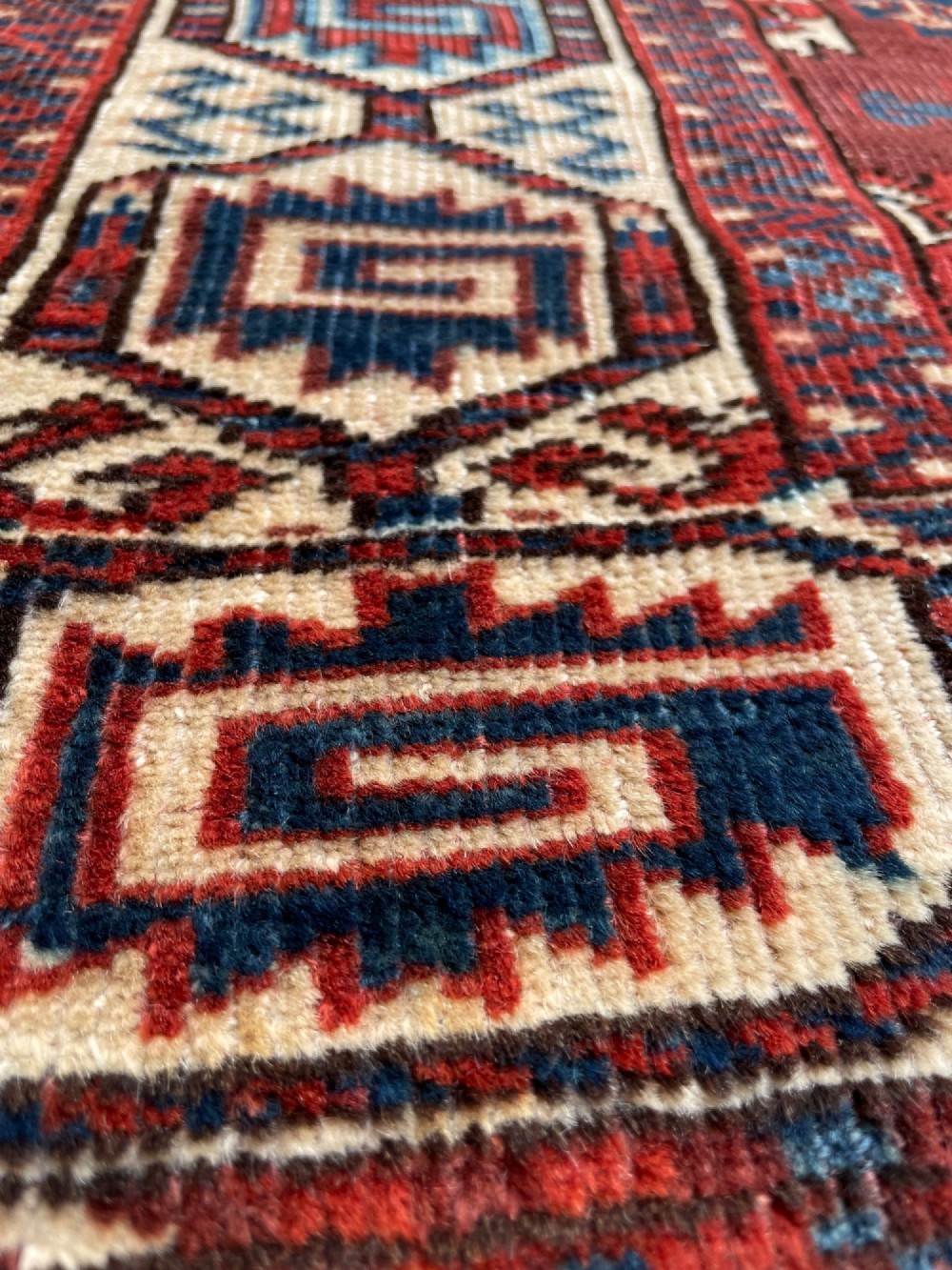 A large antique hand-knotted wool Turkoman Yomut carpet featuring repeating geometric gol motifs on a deep red ground surrounded by geometric borders. View V