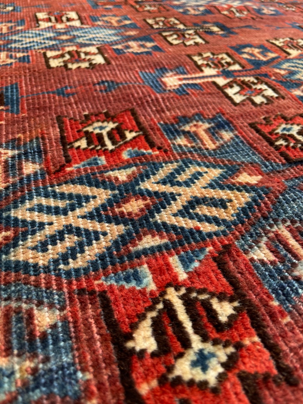 A large antique hand-knotted wool Turkoman Yomut carpet featuring repeating geometric gol motifs on a deep red ground surrounded by geometric borders. View VIII