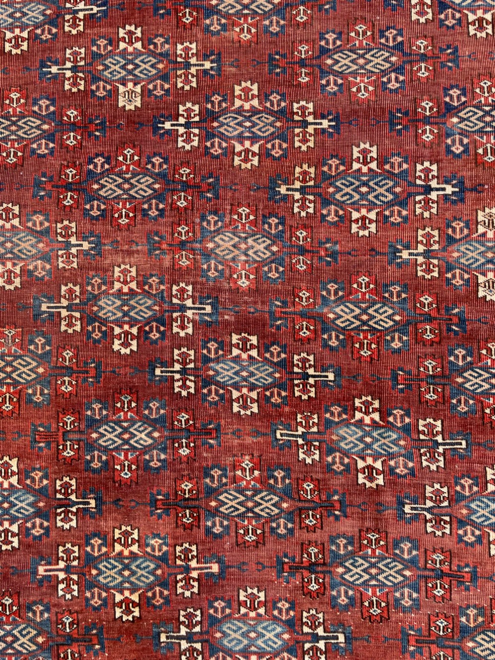 A large antique hand-knotted wool Turkoman Yomut carpet featuring repeating geometric gol motifs on a deep red ground surrounded by geometric borders. View IX