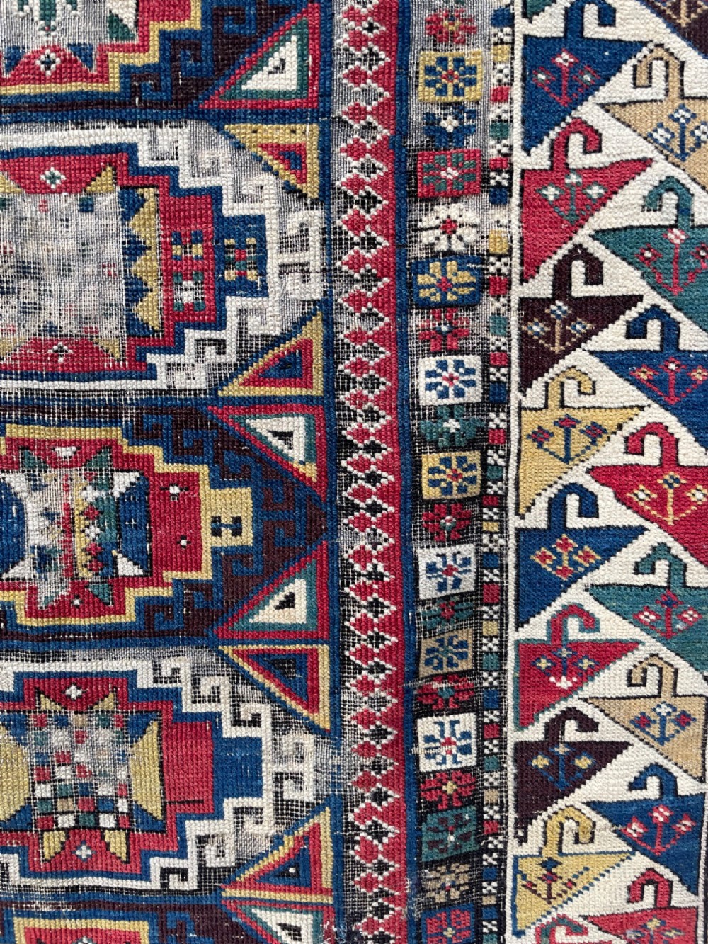 A long hand-knotted wool Shirvan runner rug featuring a central row of geometric stepped medallions framed by detailed multi-coloured bird and hook borders. View V
