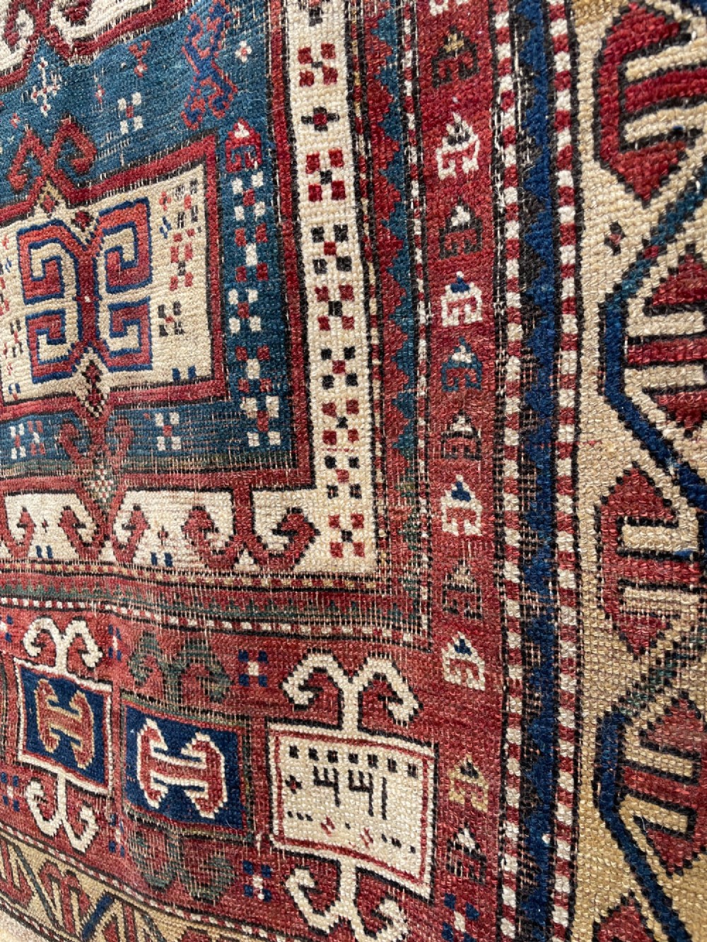An antique Caucasian Fachralo wool prayer rug featuring a central red field, an ivory geometric mihrab arch, and traditional patterned borders. View III