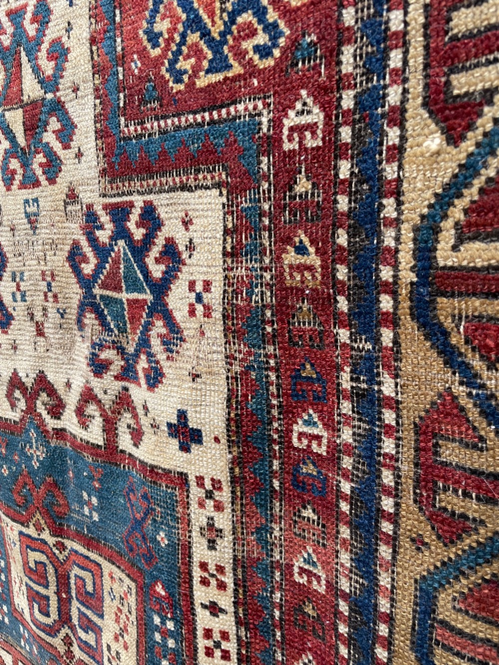 An antique Caucasian Fachralo wool prayer rug featuring a central red field, an ivory geometric mihrab arch, and traditional patterned borders. View IV