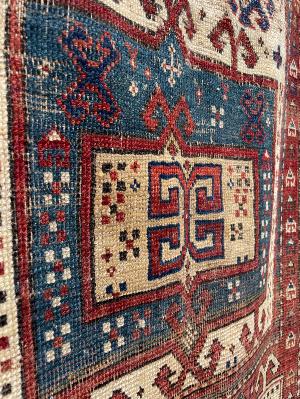 An antique Caucasian Fachralo wool prayer rug featuring a central red field, an ivory geometric mihrab arch, and traditional patterned borders. View V