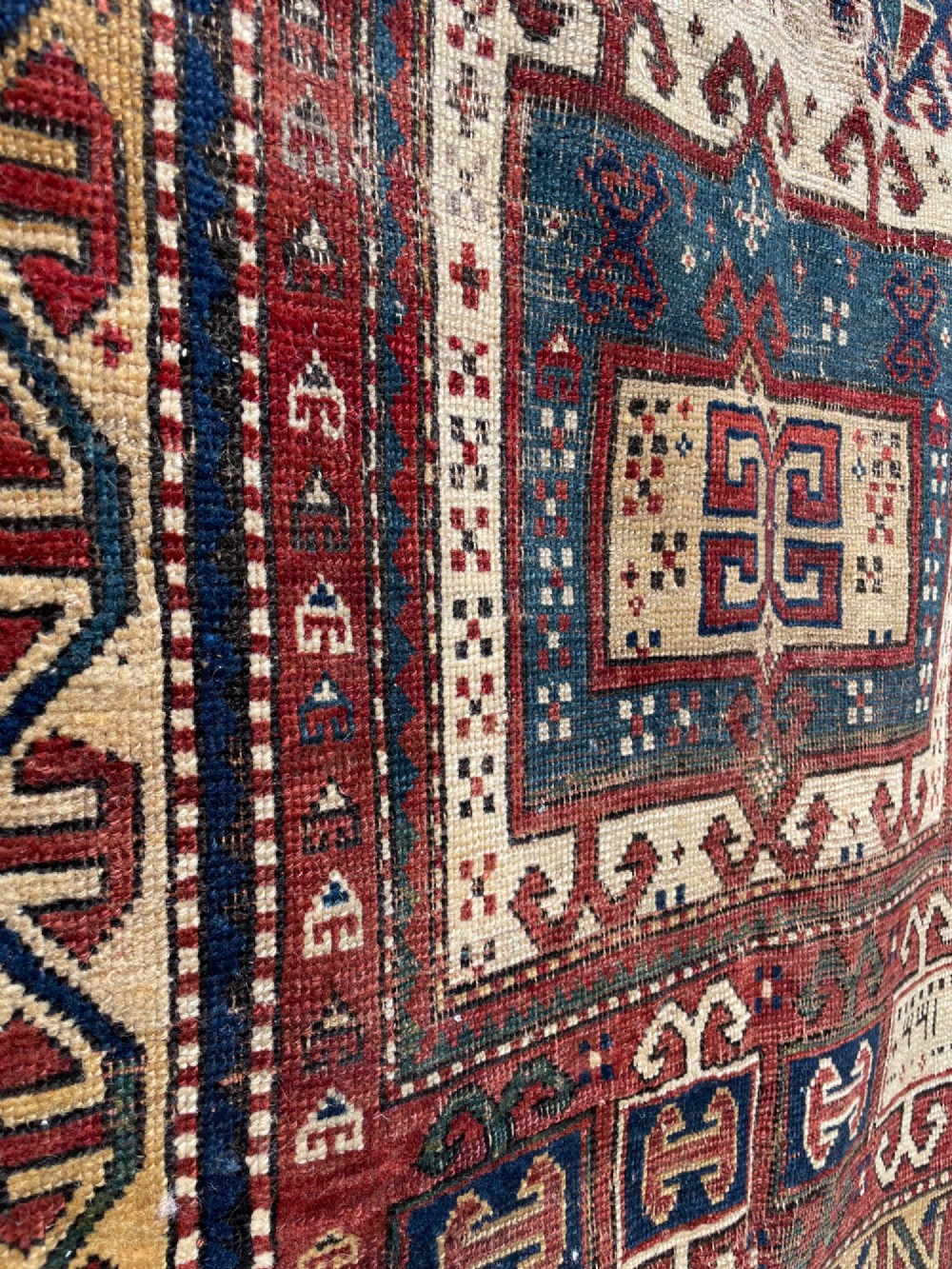 An antique Caucasian Fachralo wool prayer rug featuring a central red field, an ivory geometric mihrab arch, and traditional patterned borders. View VI