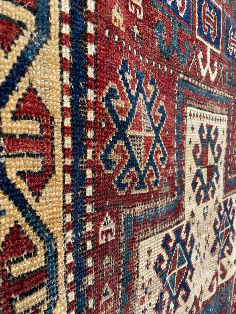 An antique Caucasian Fachralo wool prayer rug featuring a central red field, an ivory geometric mihrab arch, and traditional patterned borders. View VII