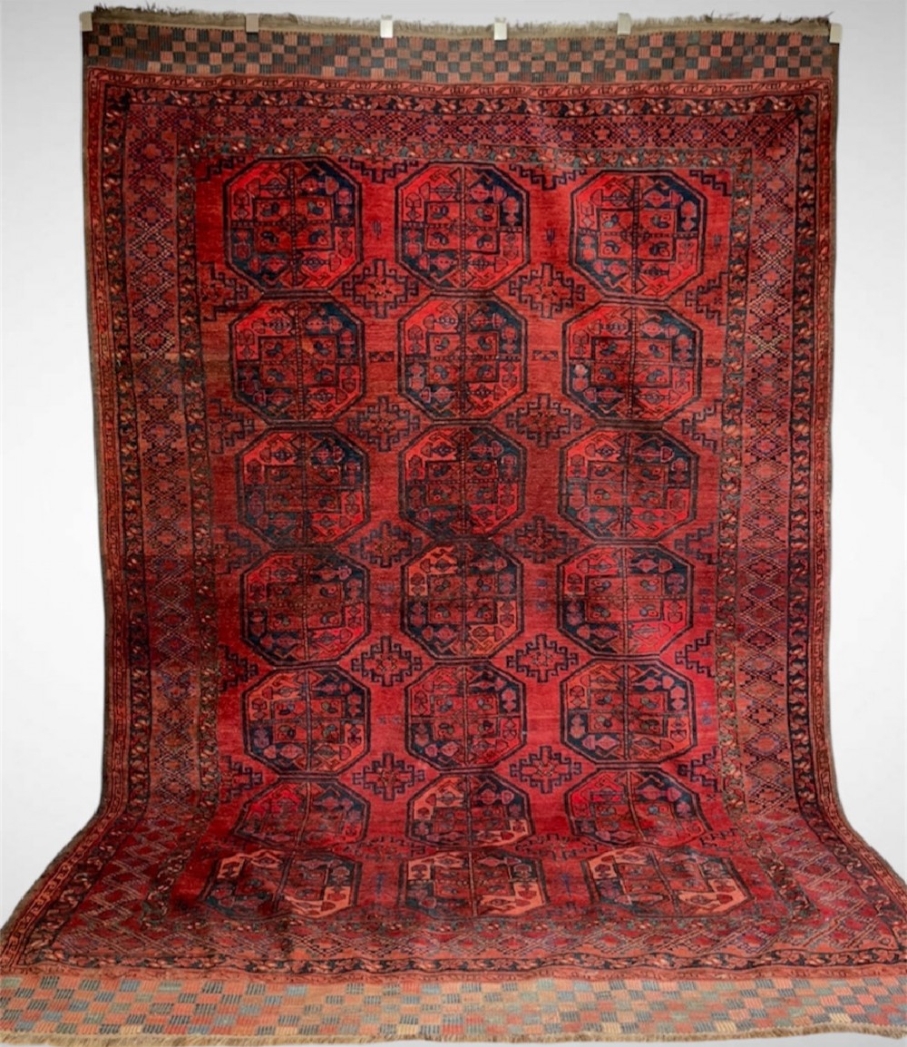 An antique Afghan Ersari hand-knotted wool carpet featuring repeating octagonal gol motifs on a deep red field with geometric borders.