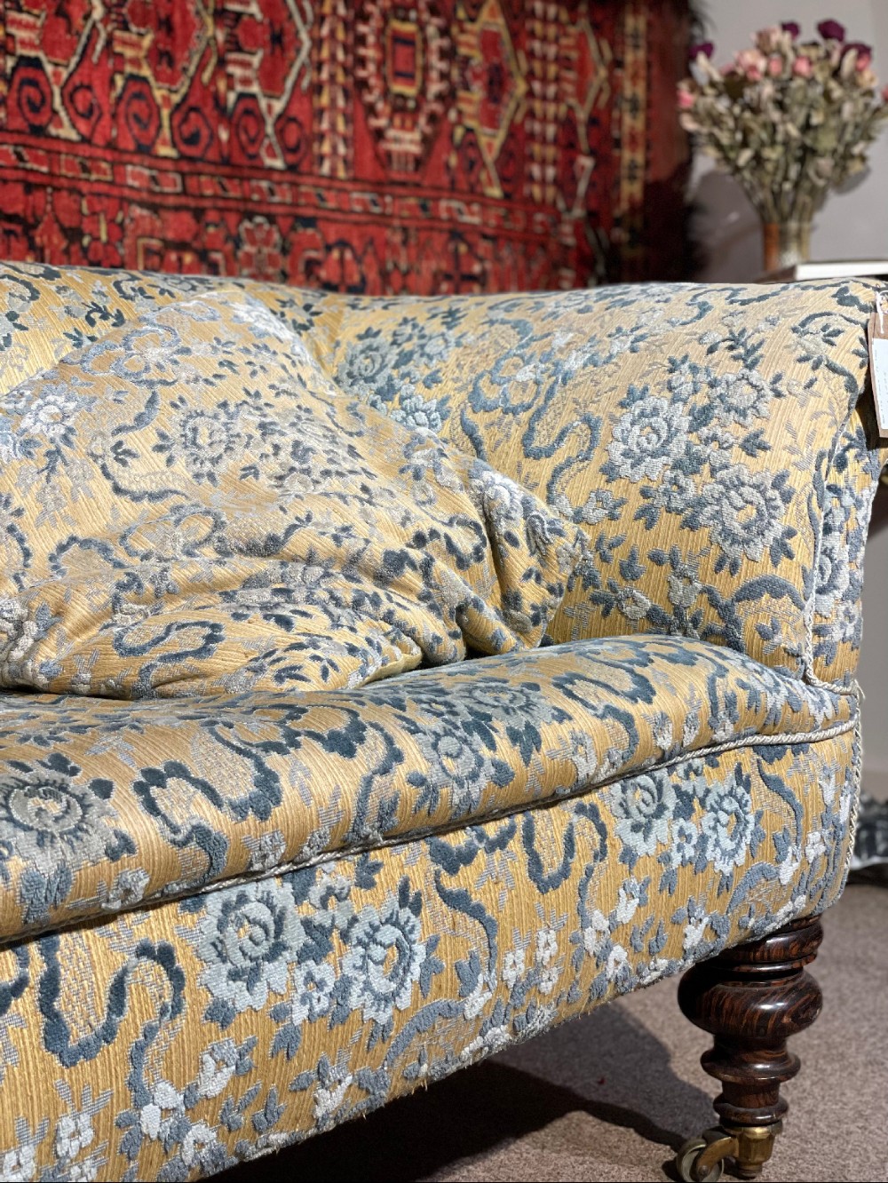 A 19th-century Victorian Chesterfield sofa upholstered in yellow floral patterned fabric with rolled arms and turned wooden legs on castors. View II