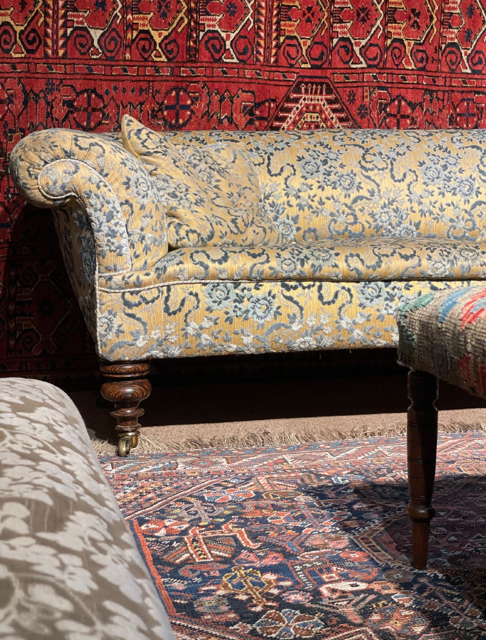 A 19th-century Victorian Chesterfield sofa upholstered in yellow floral patterned fabric with rolled arms and turned wooden legs on castors. View III