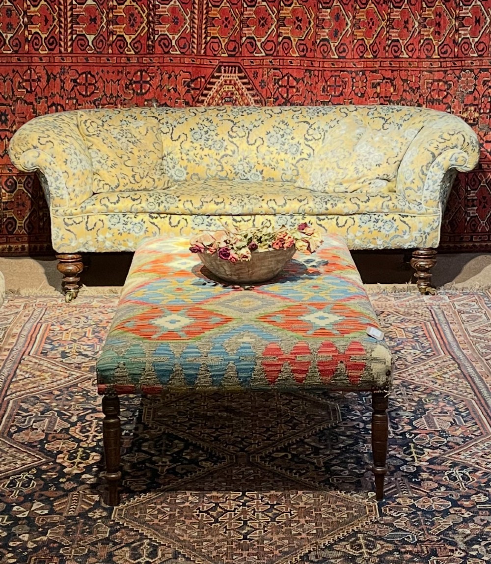 A 19th-century Victorian Chesterfield sofa upholstered in yellow floral patterned fabric with rolled arms and turned wooden legs on castors. View IV