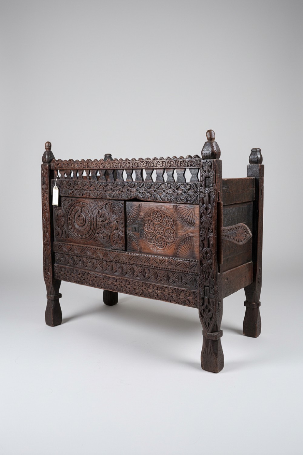 A hand-carved dark wood Swat Valley dowry chest featuring geometric rosettes, corner posts, and an open lattice gallery along the top edge.