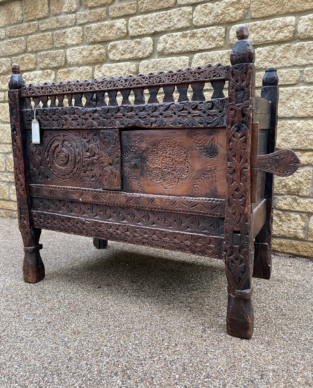 A hand-carved dark wood Swat Valley dowry chest featuring geometric rosettes, corner posts, and an open lattice gallery along the top edge. View II