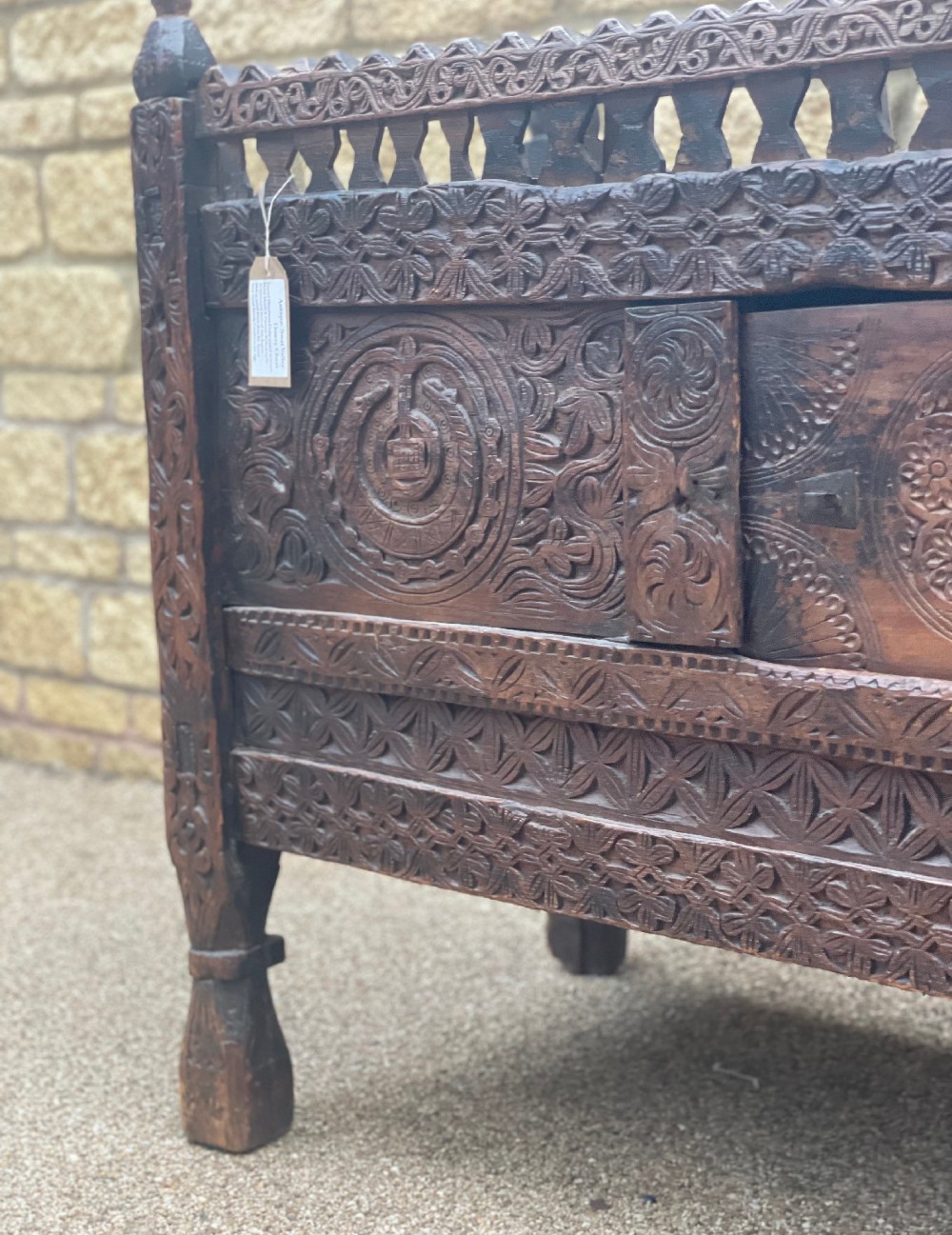 A hand-carved dark wood Swat Valley dowry chest featuring geometric rosettes, corner posts, and an open lattice gallery along the top edge. View III