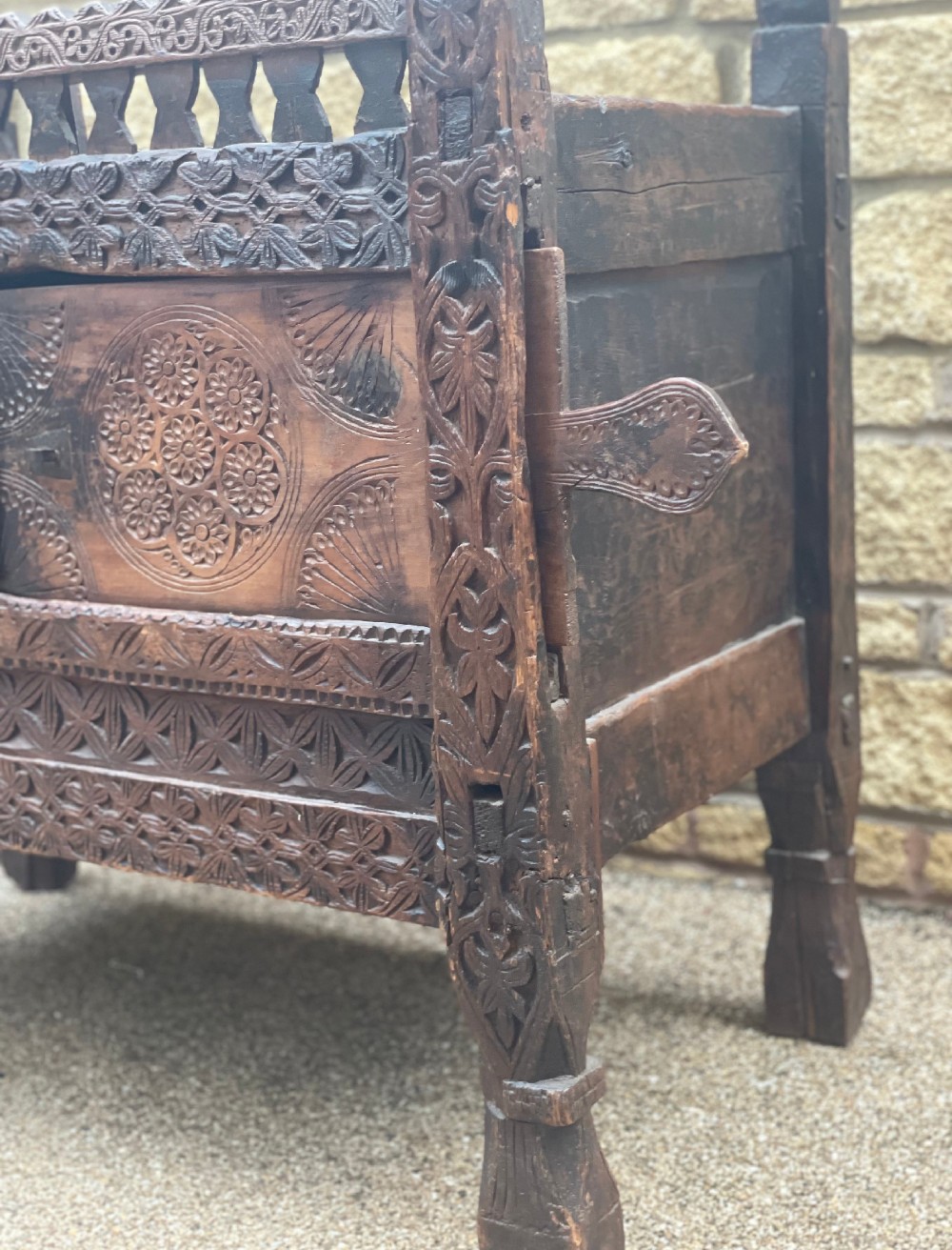 A hand-carved dark wood Swat Valley dowry chest featuring geometric rosettes, corner posts, and an open lattice gallery along the top edge. View IV