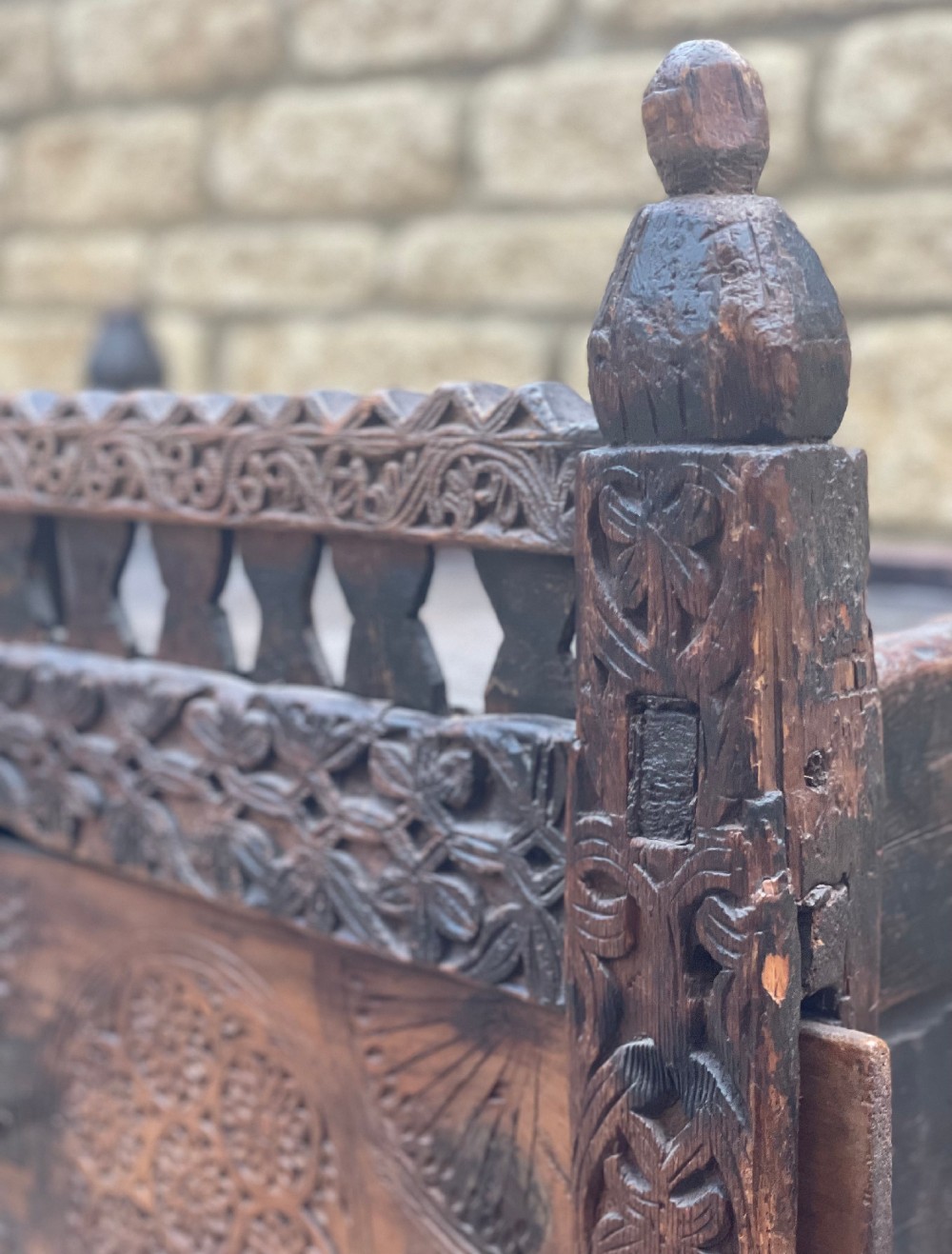 A hand-carved dark wood Swat Valley dowry chest featuring geometric rosettes, corner posts, and an open lattice gallery along the top edge. View V