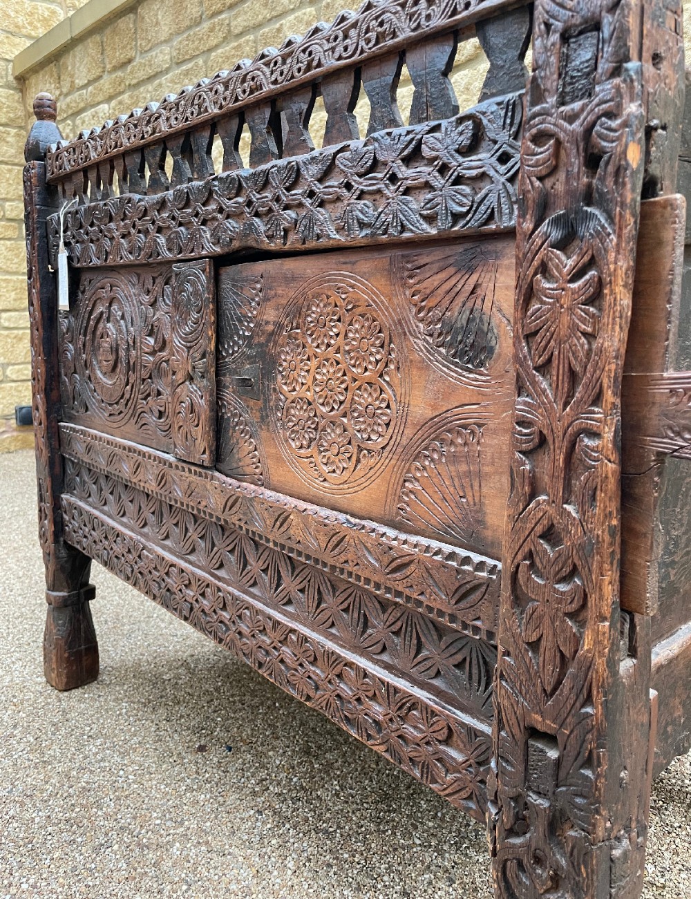 A hand-carved dark wood Swat Valley dowry chest featuring geometric rosettes, corner posts, and an open lattice gallery along the top edge. View VIII