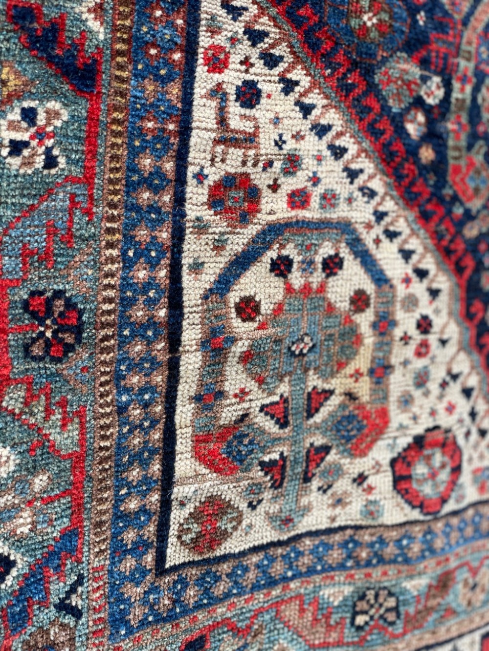 An antique hand-knotted wool carpet displaying a central diamond medallion, geometric borders, and an indigo field filled with intricate tribal motifs. View II