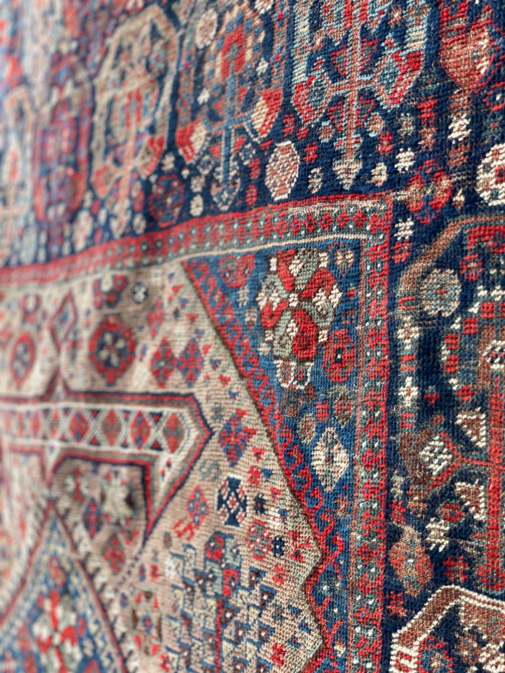 An antique hand-knotted wool carpet displaying a central diamond medallion, geometric borders, and an indigo field filled with intricate tribal motifs. View IV